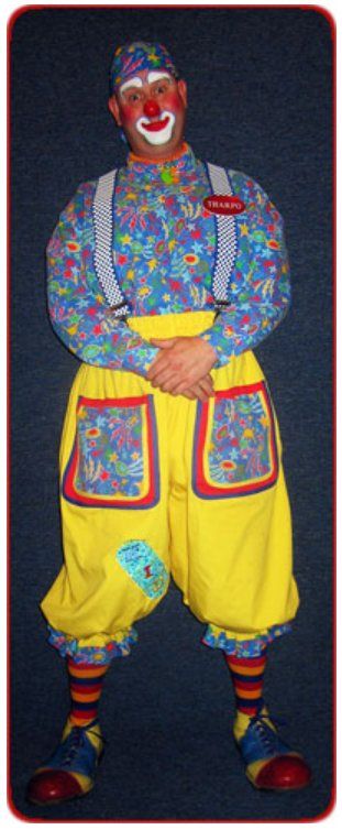 A man dressed as a clown is standing with his arms crossed