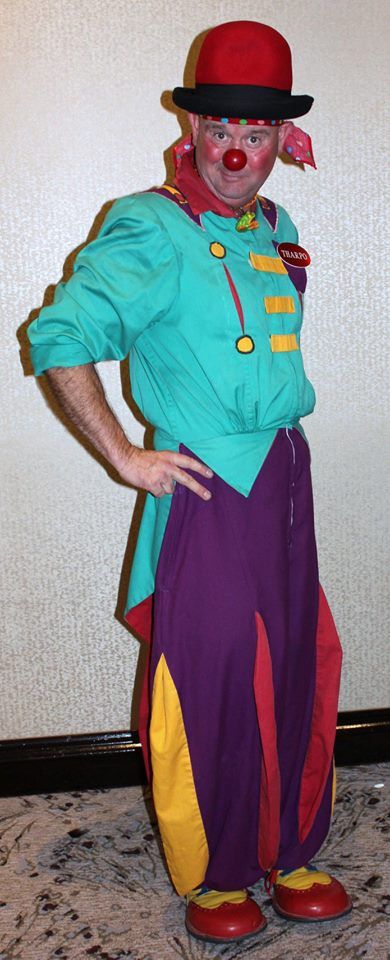 A man dressed as a clown is standing with his hands on his hips.