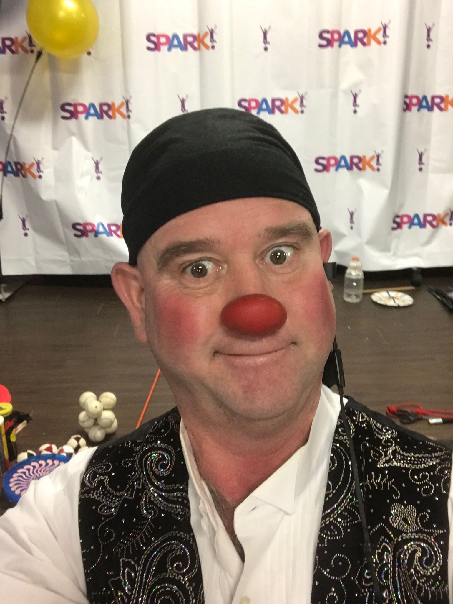A man with a red nose is wearing a black headband