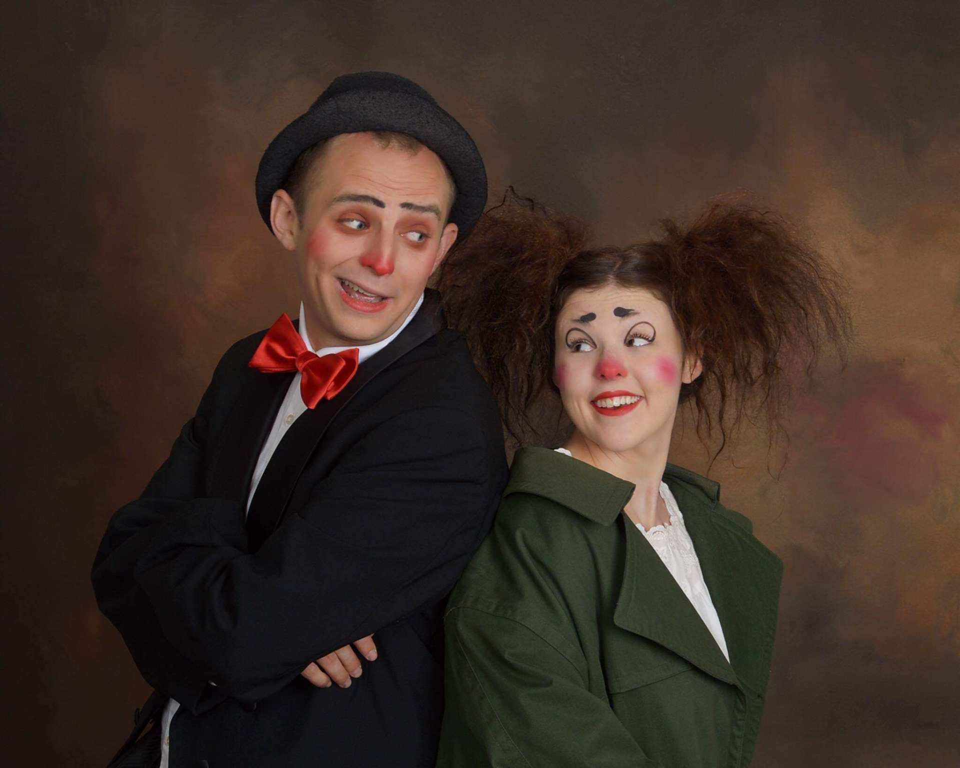 A man and a woman dressed as clowns are posing for a picture.