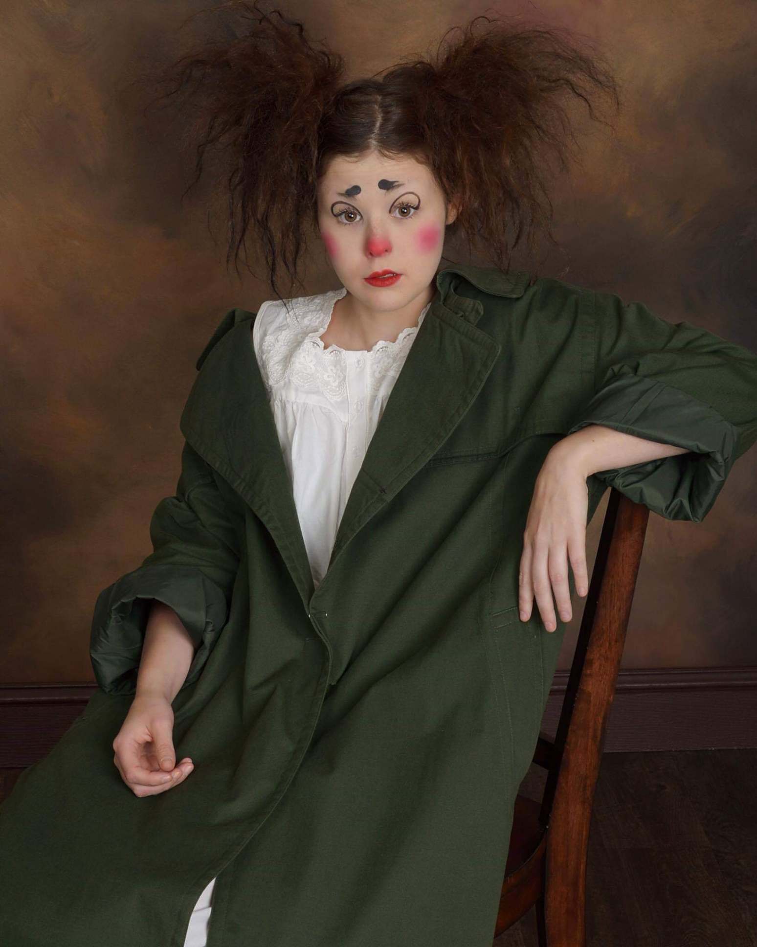 A woman in a clown costume is sitting on a chair