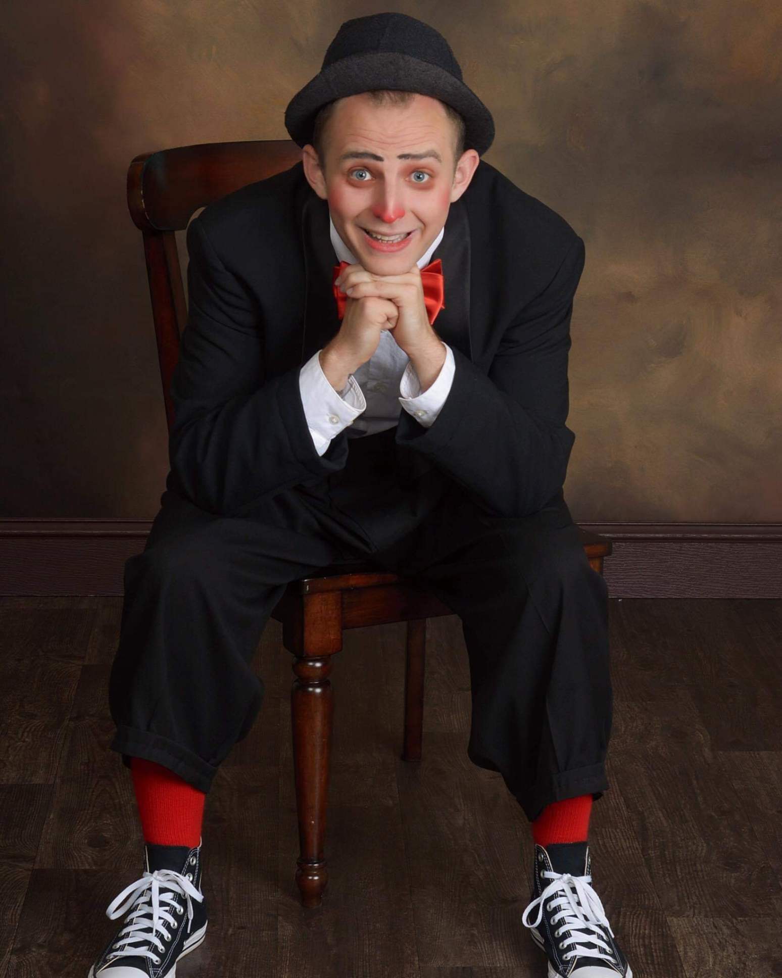 A man in a tuxedo and hat is sitting in a chair