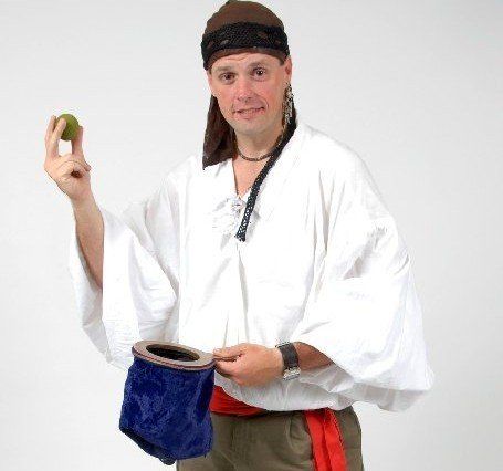 A man in a white shirt is holding a green apple and a blue bag.