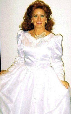 A woman in a white dress is smiling for the camera