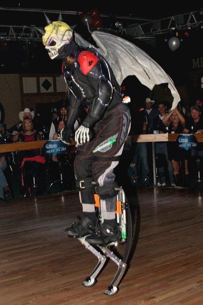 A man in a skeleton costume is jumping on stilts on a dance floor
