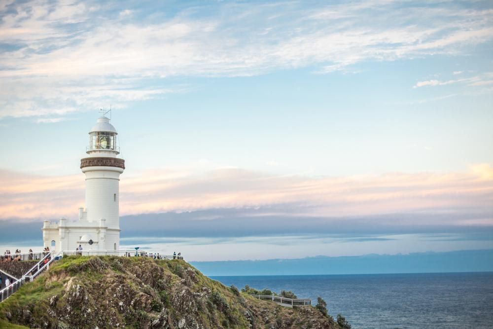 A Lighthouse Is Sitting On Top Of A Cliff Overlooking The Ocean — The Woolmen In Byron Bay, NSW