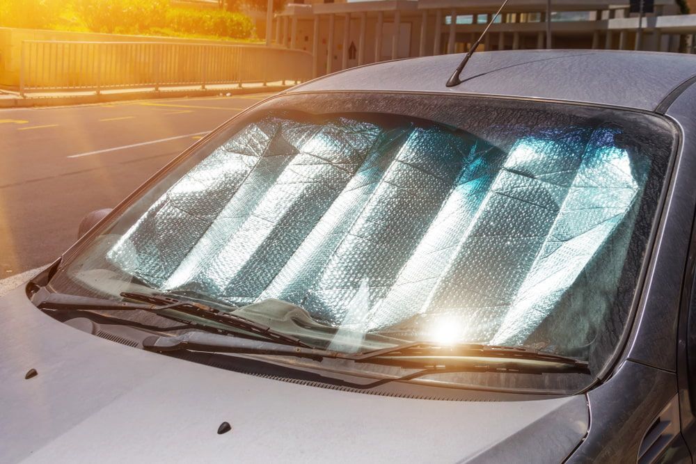 A Car With A Sun Shade On The Windshield Is Parked On The Side Of The Road — The Woolmen In Ballina, NSW