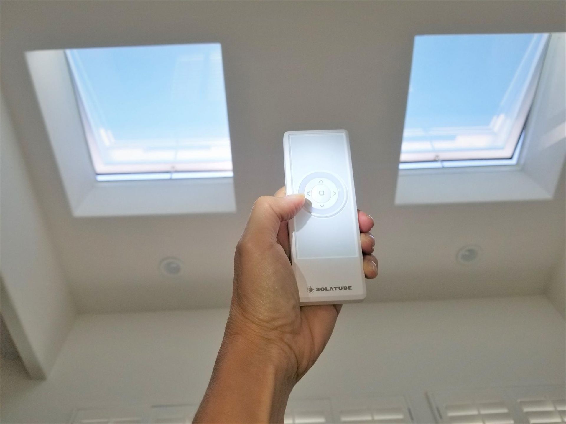 A Person Is Holding A Remote Control In Front Of Two Skylights — The Woolmen In Ballina, NSW