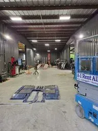 A large warehouse with a blue scissor lift in the middle of it.