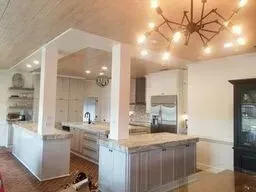 A kitchen with a large island and a chandelier hanging from the ceiling.