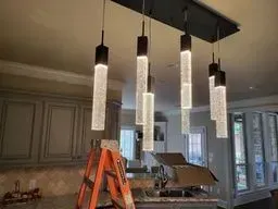 A kitchen with a ladder and a chandelier hanging from the ceiling.