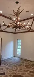 An antler chandelier is hanging from the ceiling of an empty room.
