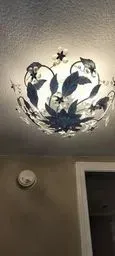 A ceiling light with a flower design on it is hanging from the ceiling of a room.