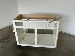 A white cabinet is sitting on a concrete floor in a room.