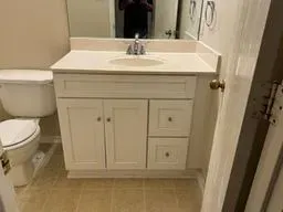A bathroom with a sink, toilet and mirror.