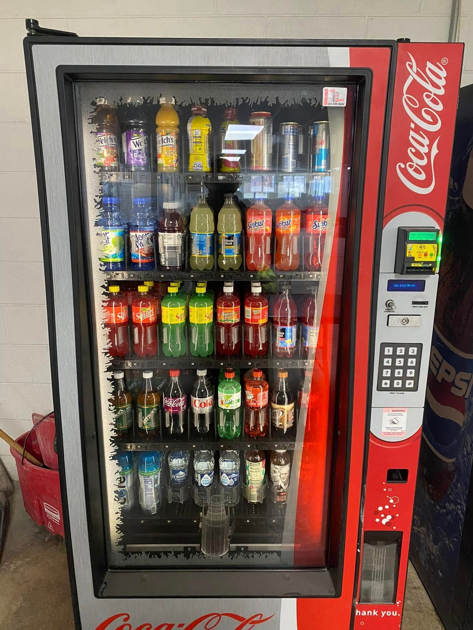 Coca-Cola vending machine filled with various drinks, red and gray design.