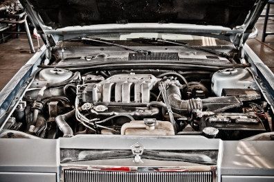 Classic car engine bay with exposed engine and chrome grille, viewed from the front with hood open