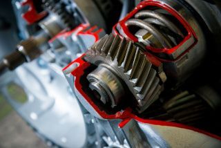 Close-up of exposed metal gears with red grease in a mechanical assembly