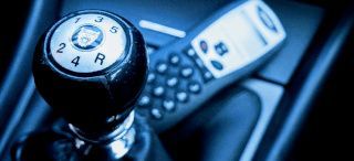Close-up of a manual gear shift knob and car keys on a dark dashboard
