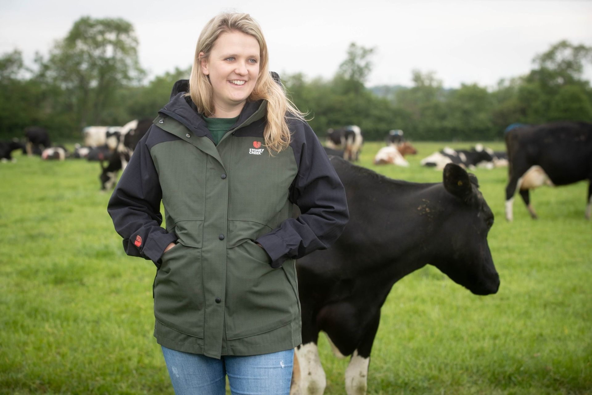 A man is sitting on the ground tying his rain boots.