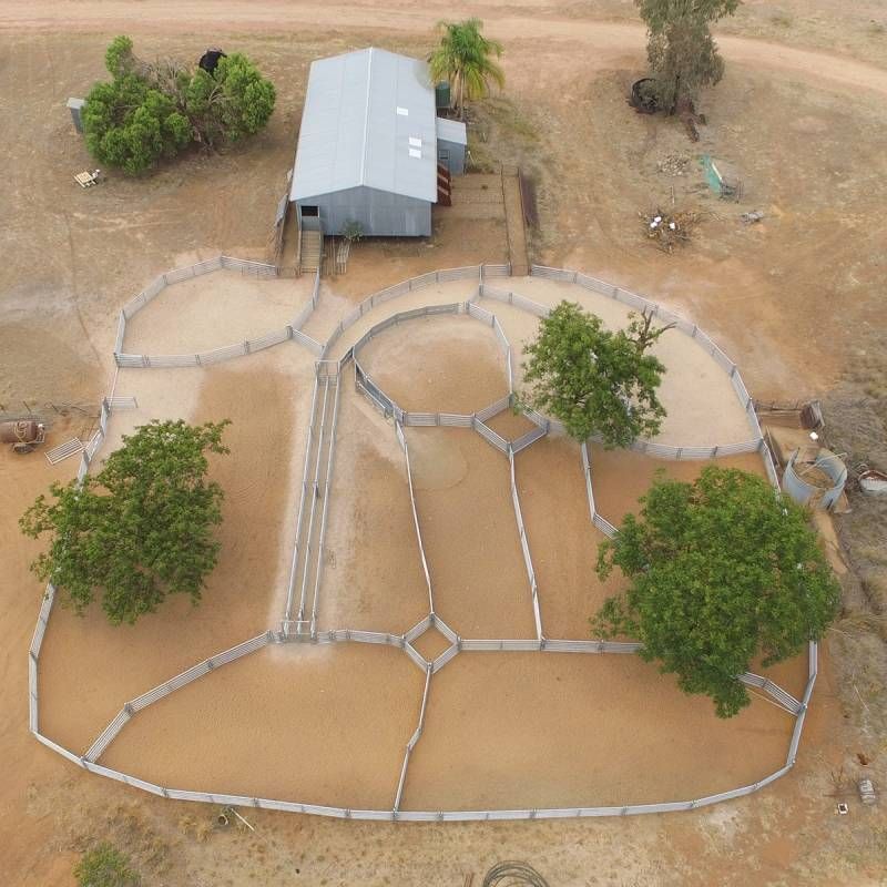 An aerial view of a fenced in area with a house in the background