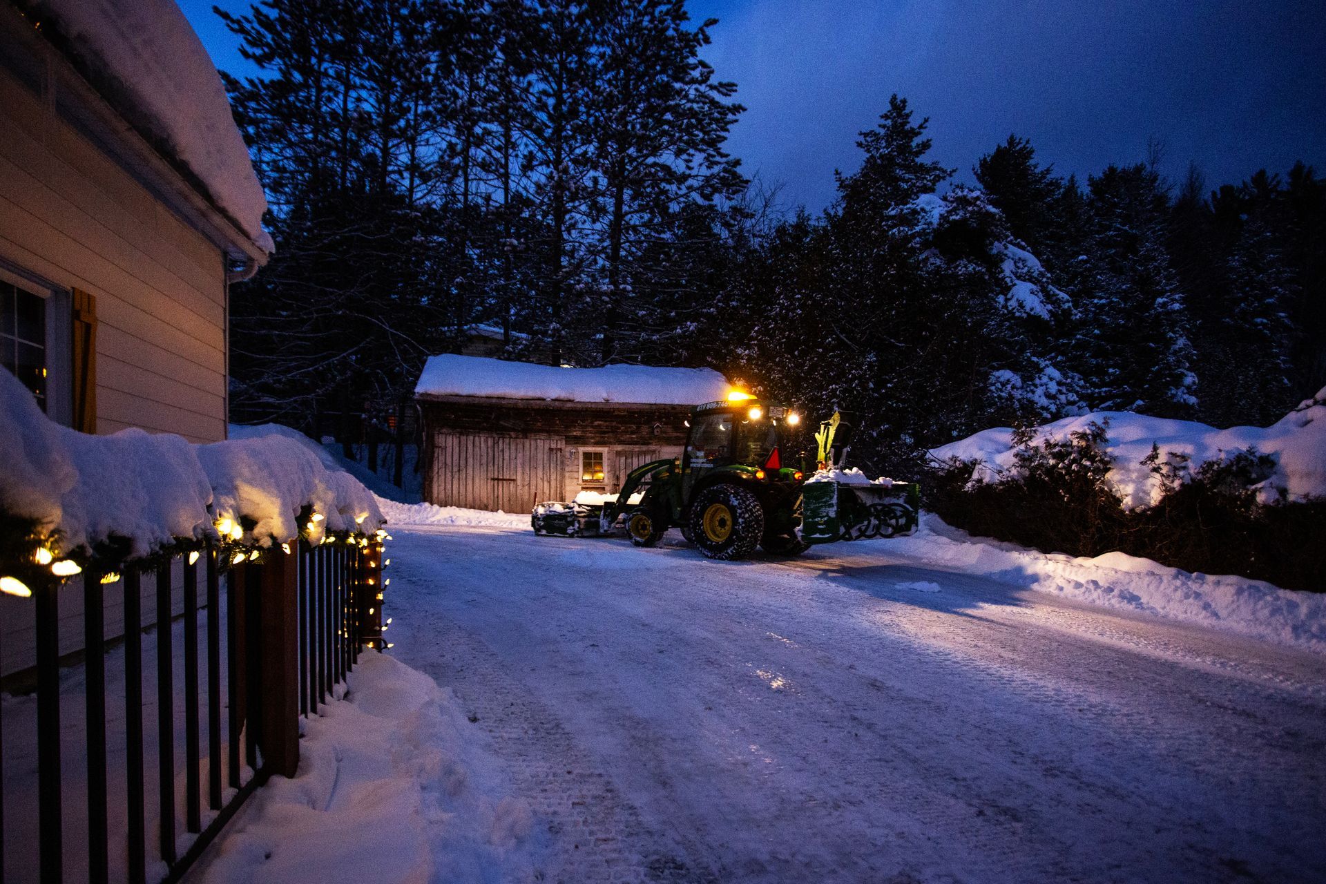 Un tracteur déneige une allée la nuit.