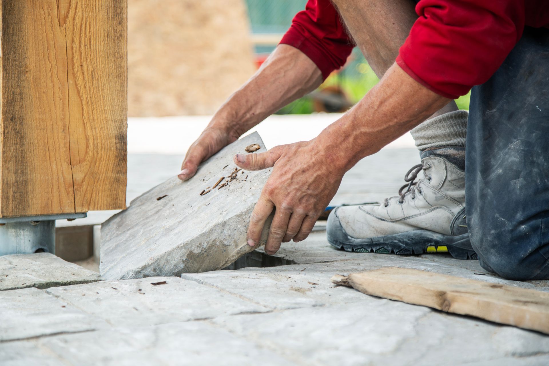 Un homme est à genoux et utilise une truelle pour étaler du béton sur un patio.