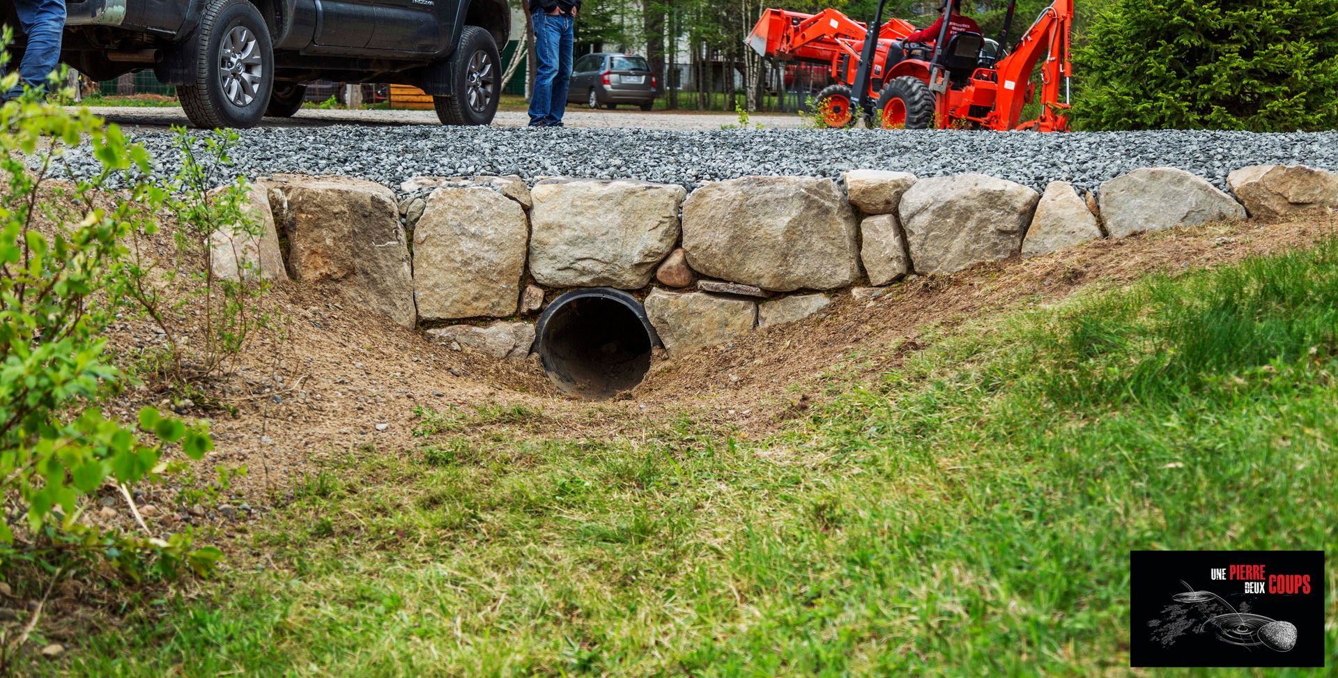 Un homme se tient debout à côté d'un tuyau dans l'herbe.