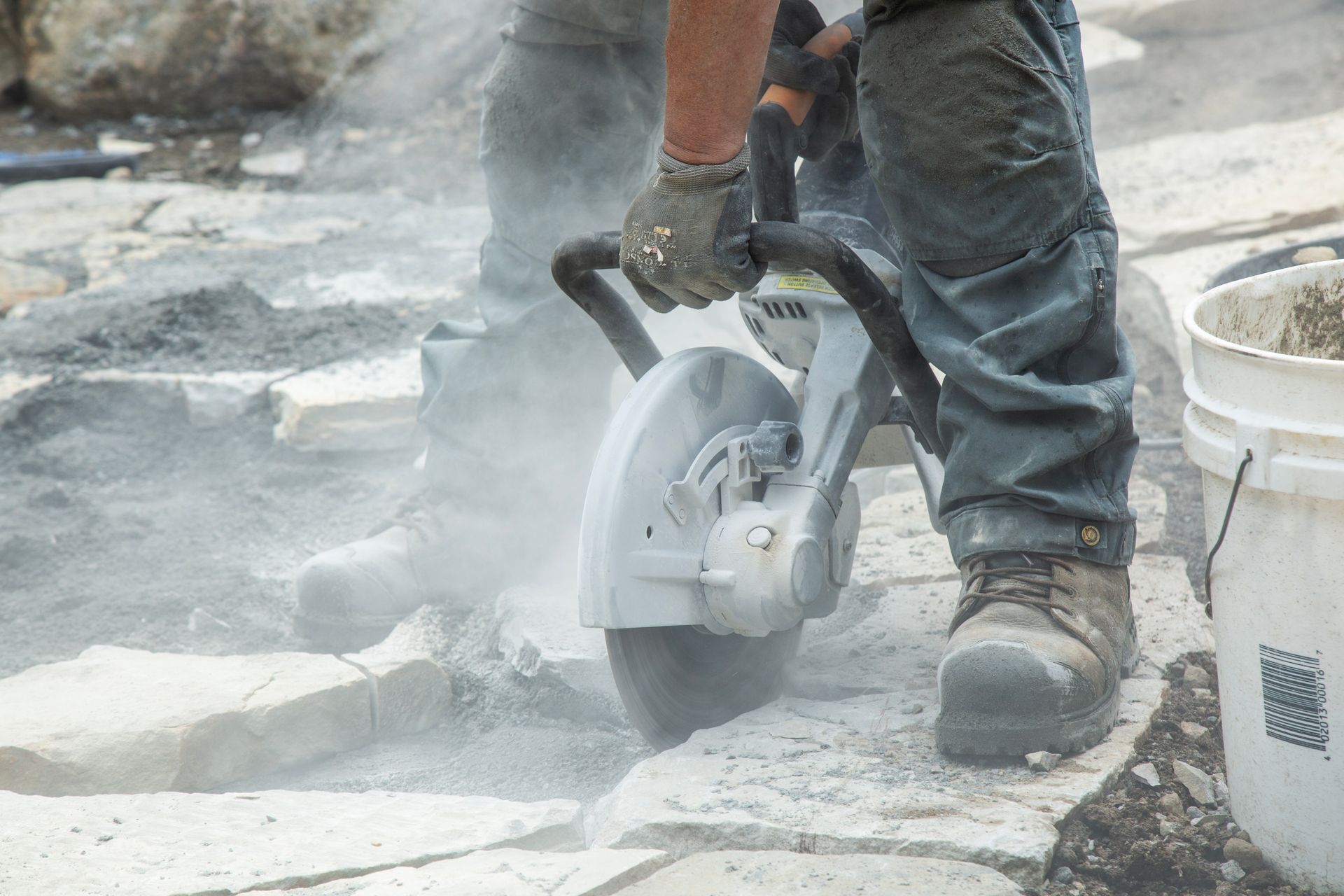 Un homme utilise une scie circulaire pour couper du béton.