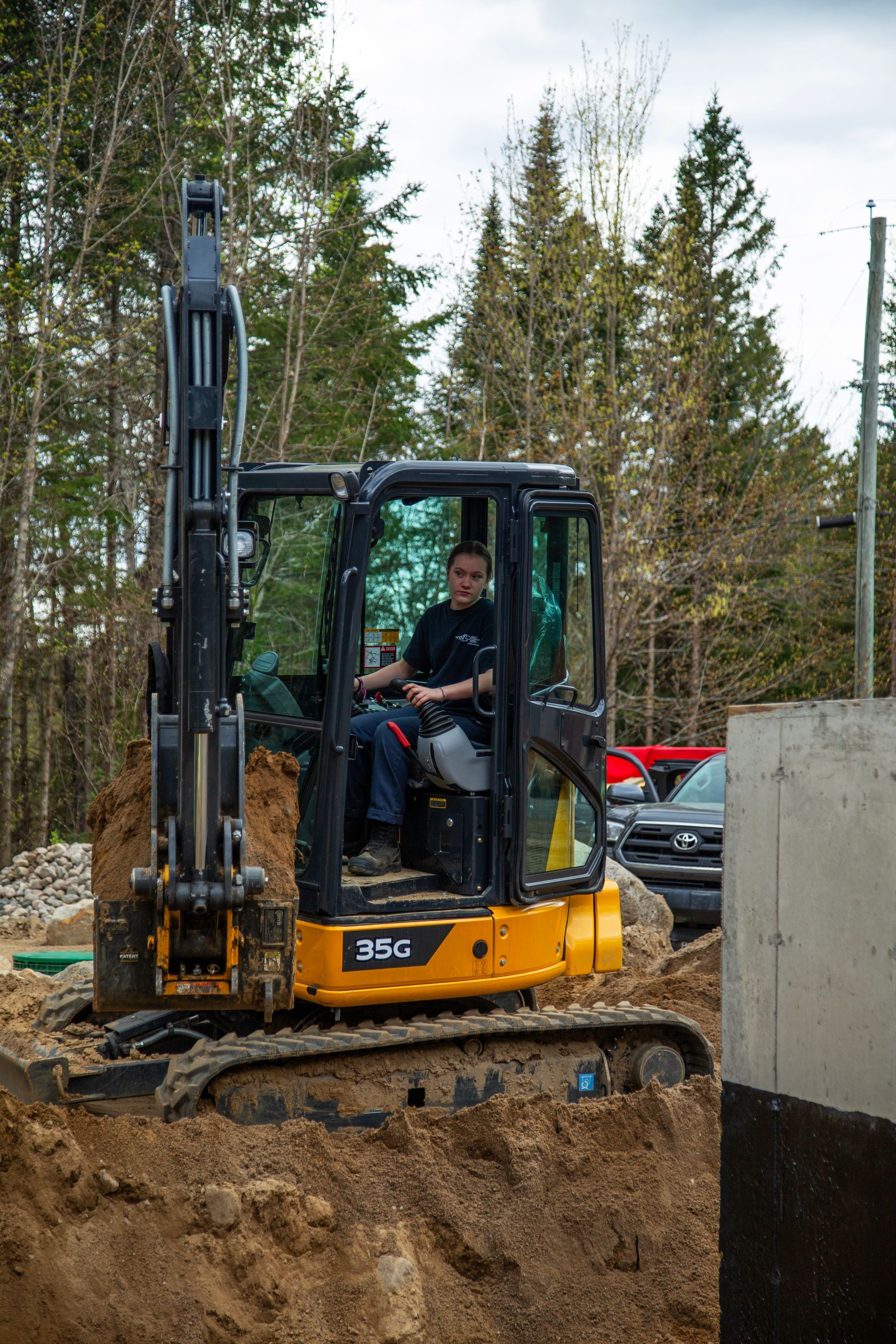 Un homme est assis sur le siège conducteur d'une petite excavatrice.