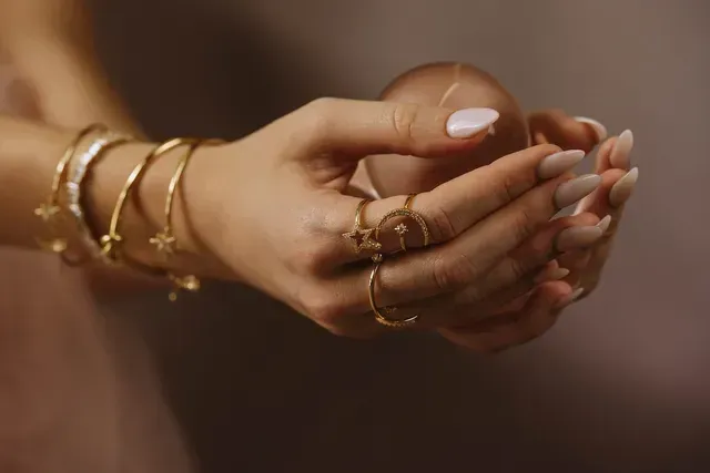 Een close-up van de handen van een vrouw met armbanden en ringen.