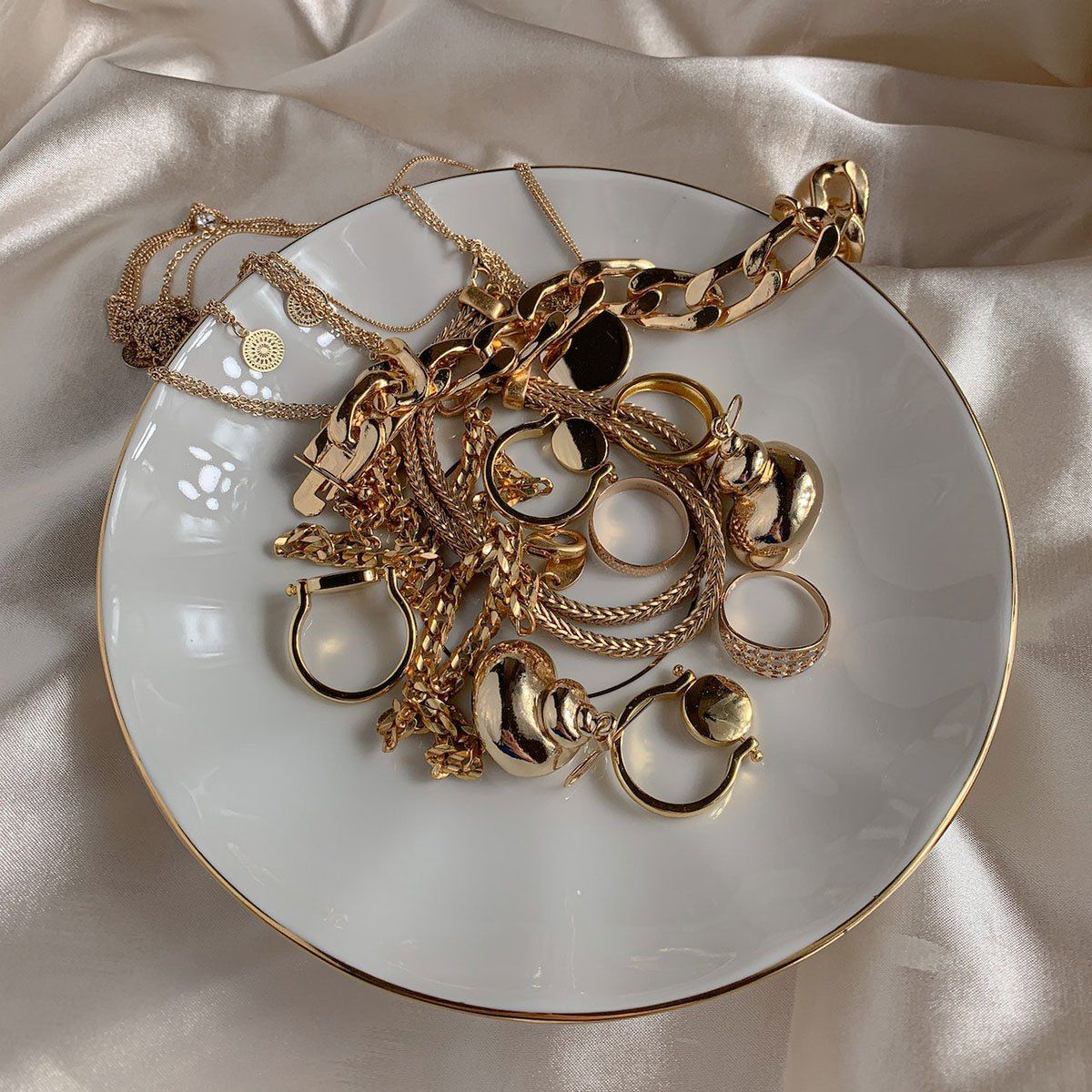 Een wit bord met daarop een bos gouden sieraden.