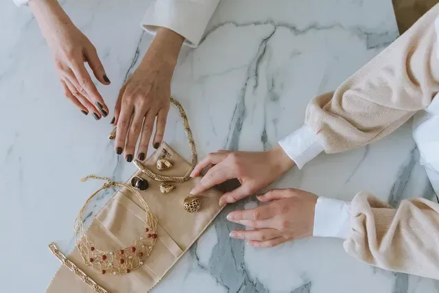 Twee vrouwen zitten aan een tafel en kijken naar sieraden.