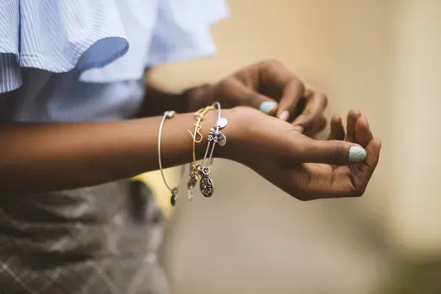 Een vrouw draagt veel armbanden om haar pols.