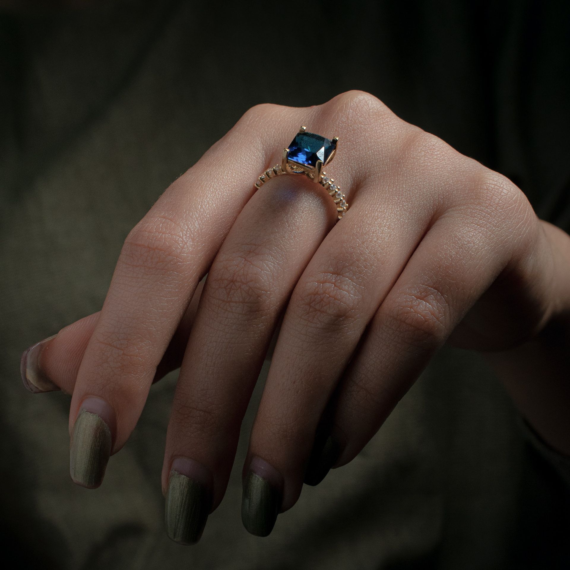 Een vrouw die een ring met een blauwe steen aan haar vinger draagt
