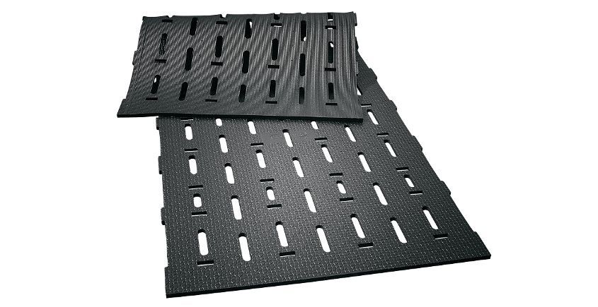 Tapis de sol noirs emboîtables avec ouvertures fendues, empilés.