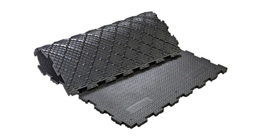 Tapis de sol en caoutchouc noir emboîtables, partiellement enroulés, avec un motif en losange texturé d'un côté et une surface plane de l'autre.