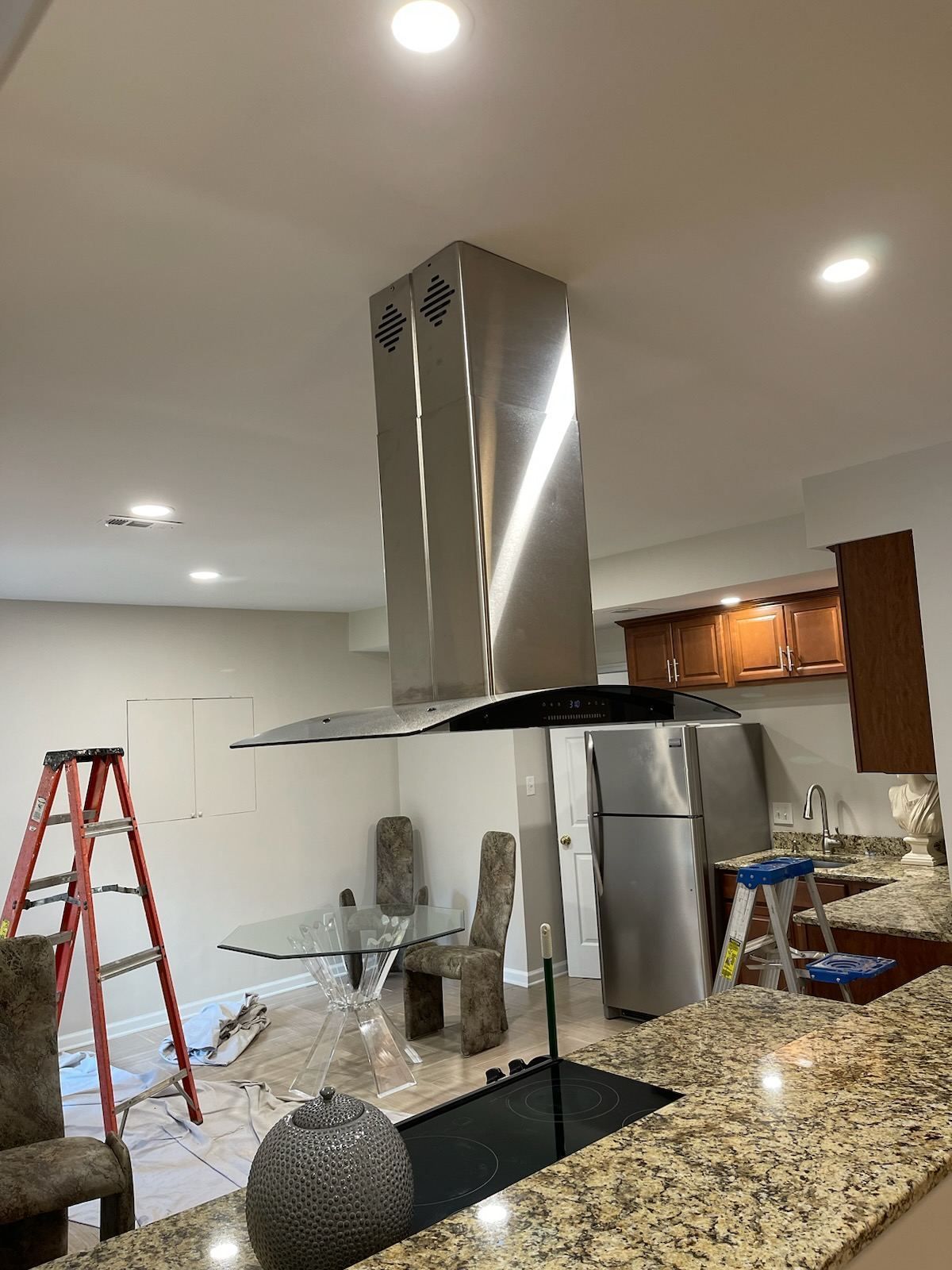 A kitchen with a stainless steel hood hanging from the ceiling.