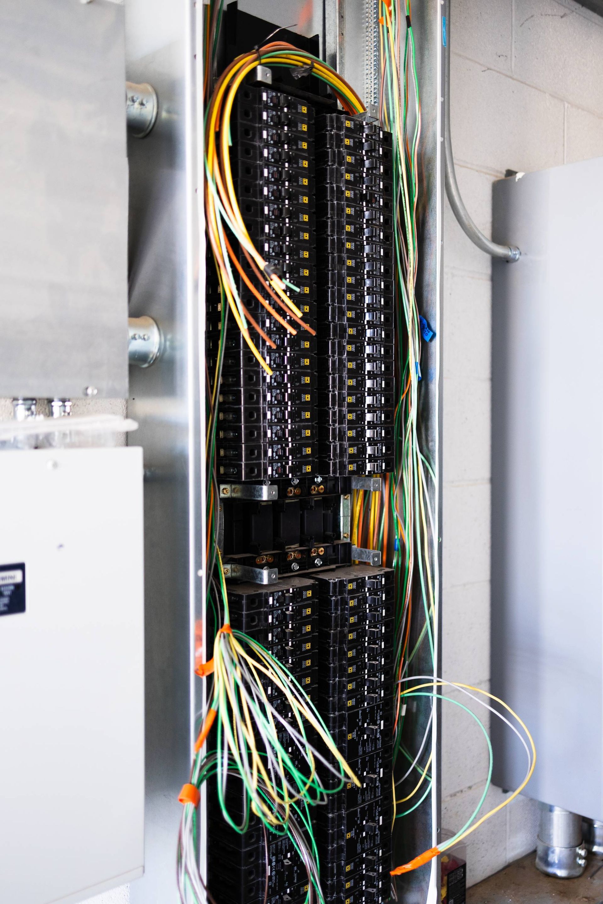 A narrow metal cabinet open, revealing racks of black fiber optic connectors and bundles of colorful cables.