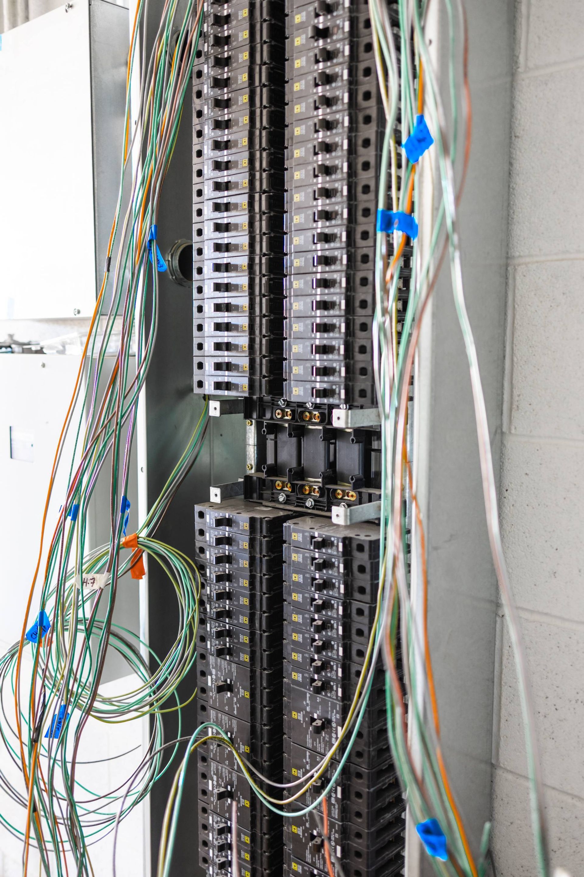 Electrical wiring cabinet with numerous wires, mostly green, extending from rows of metallic panels.