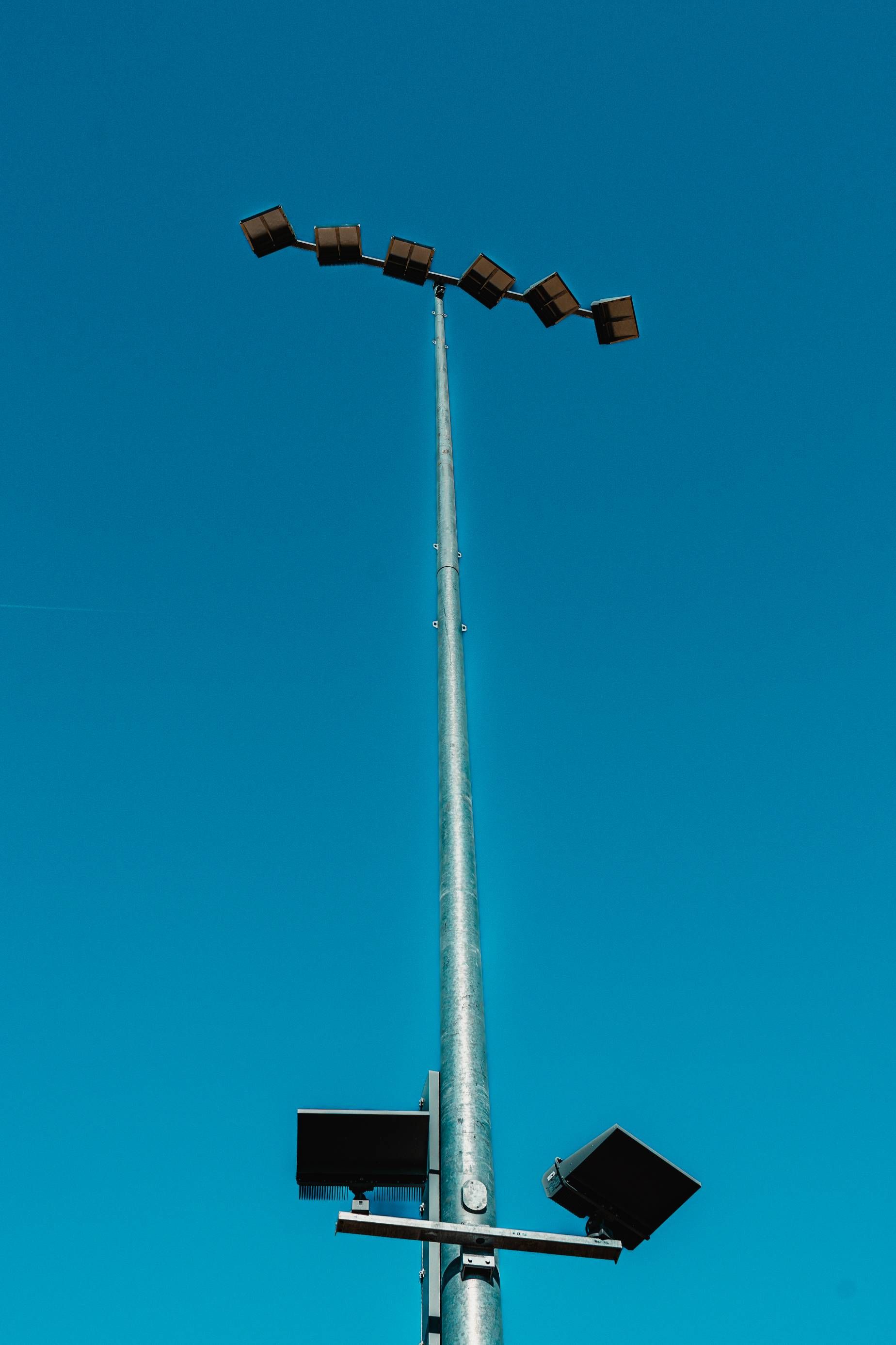 Tall stadium light pole with several lights against a clear, blue sky.
