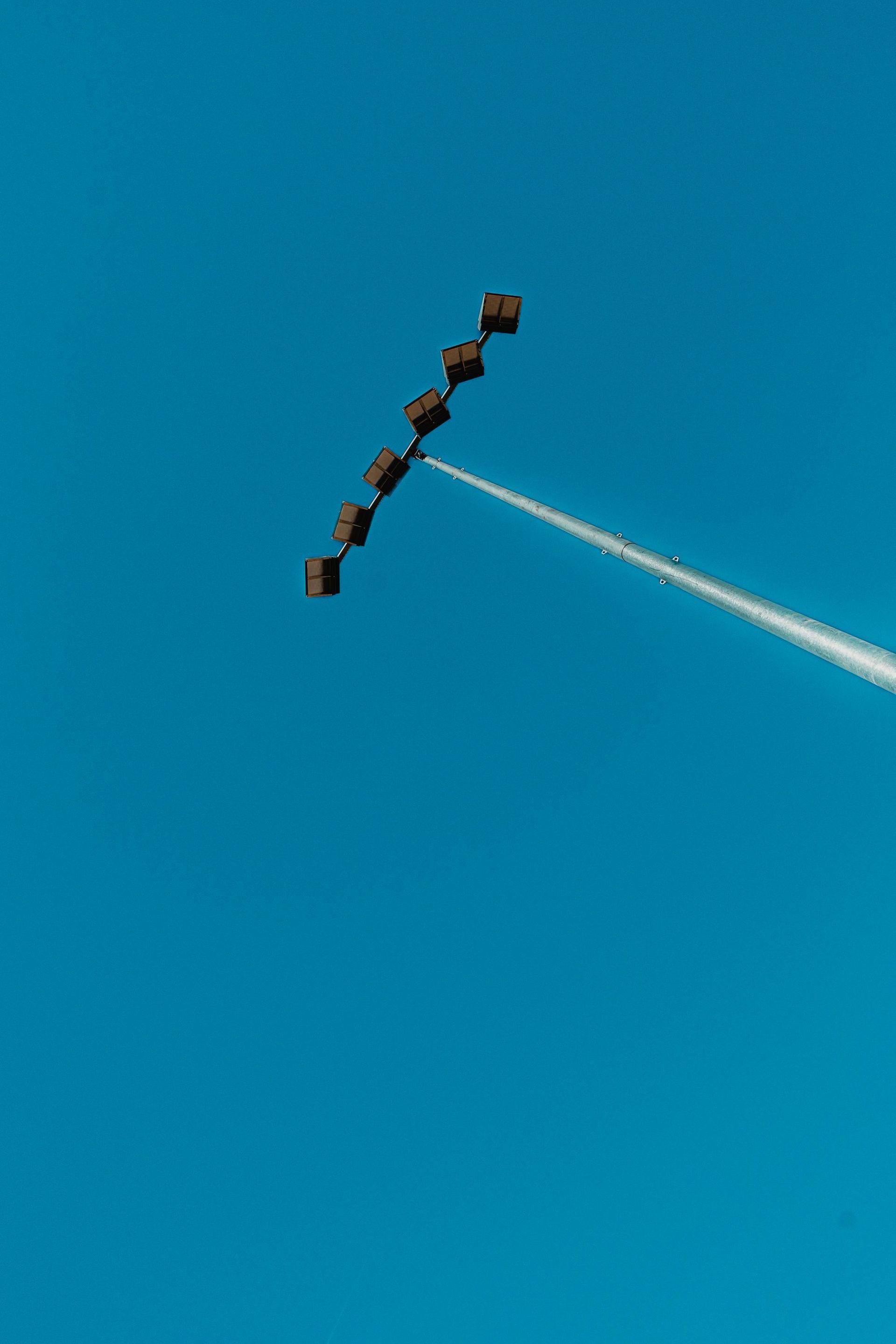 Formation of six dark-colored aircraft flying in a line formation with a white contrail against a clear blue sky.