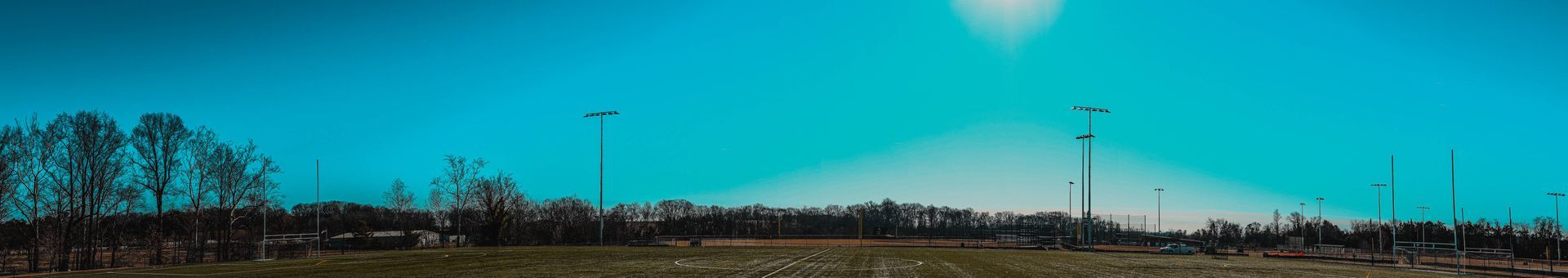 Sky with electric poles and trees in a field. Bright light from the sun.