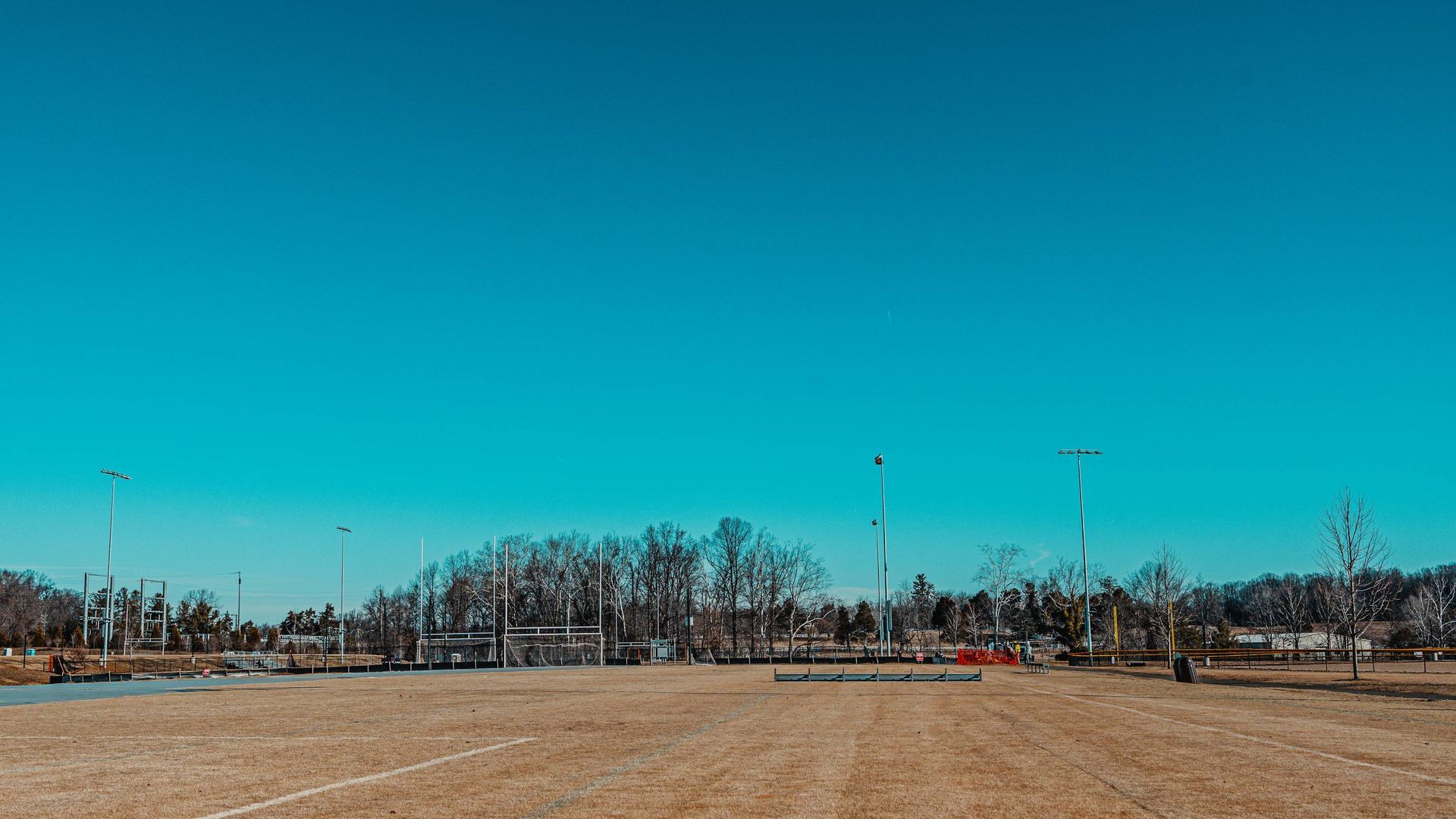 Brown field, bare trees, and blue sky with radio towers in the distance.