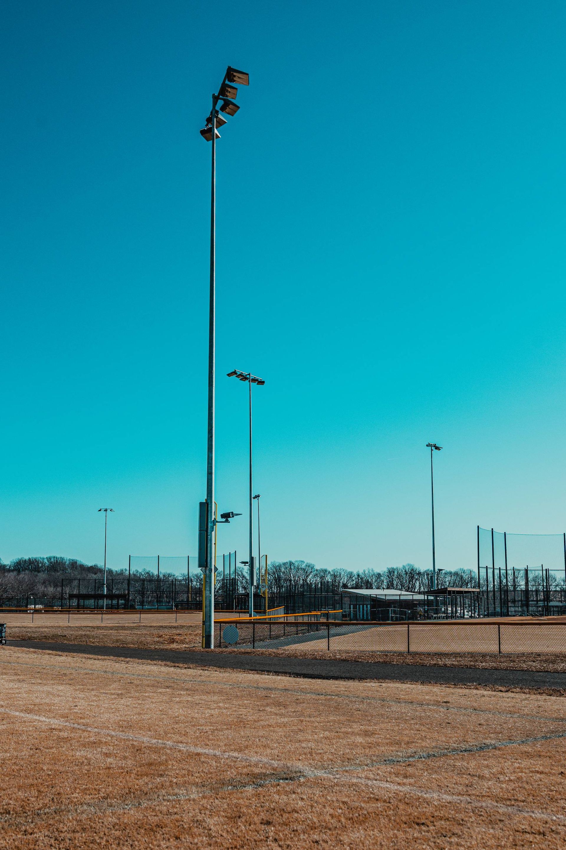 Baseball field under a bright blue sky with tall light poles.