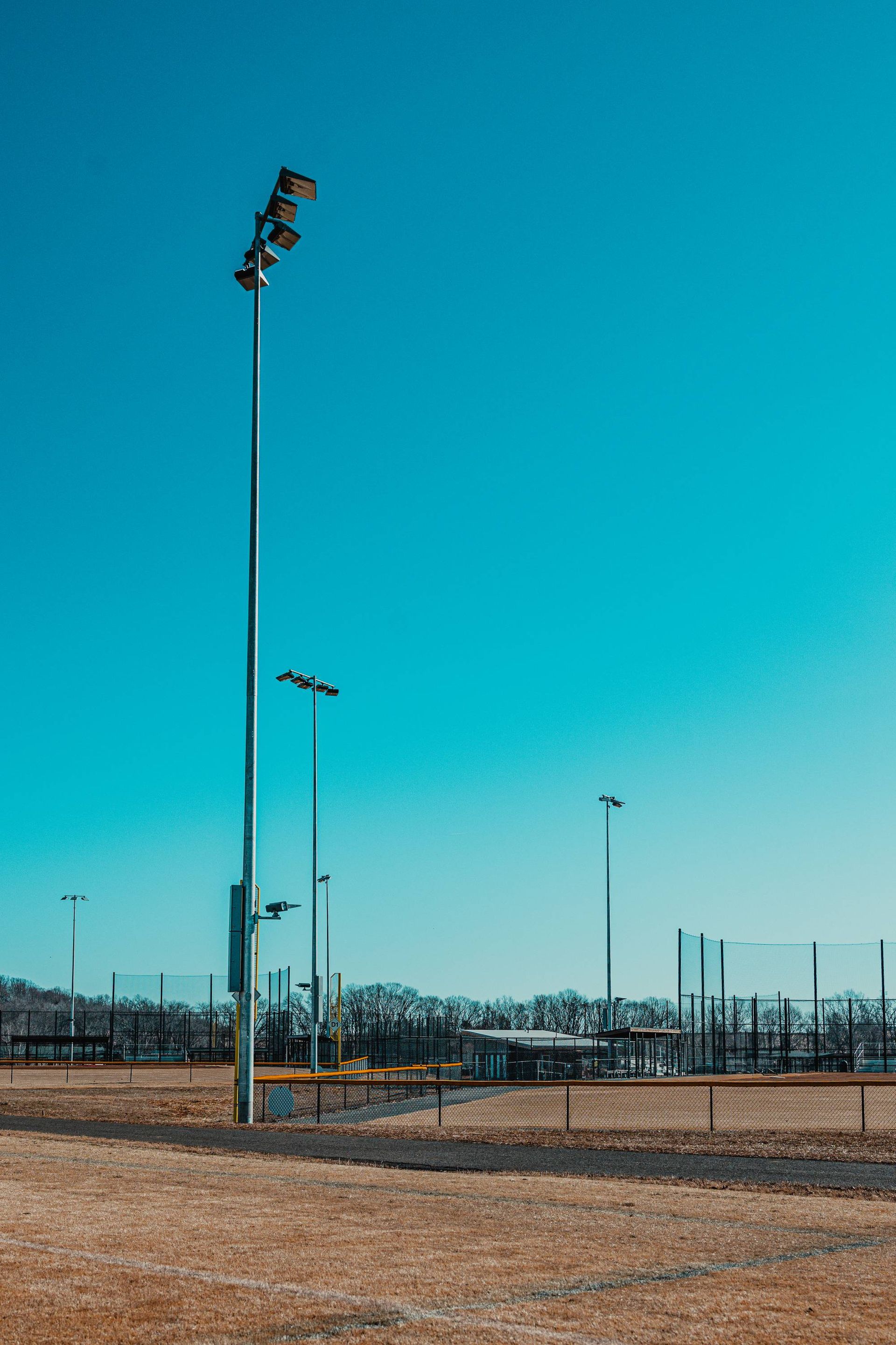 Light poles on a baseball field on a sunny day with a bright blue sky.