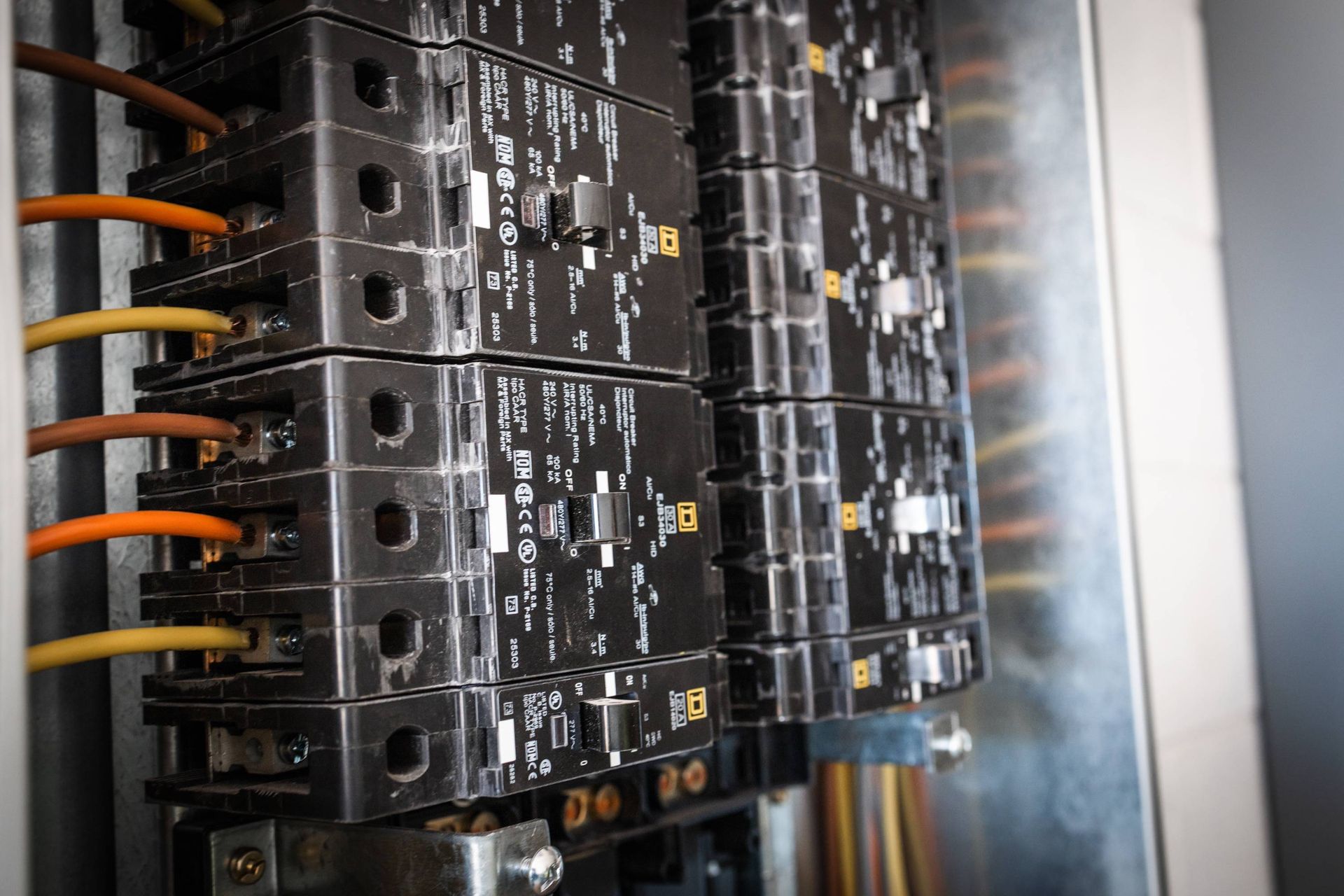 Close-up of electrical breaker panel with wires. Brown, yellow, and orange wires are visible.