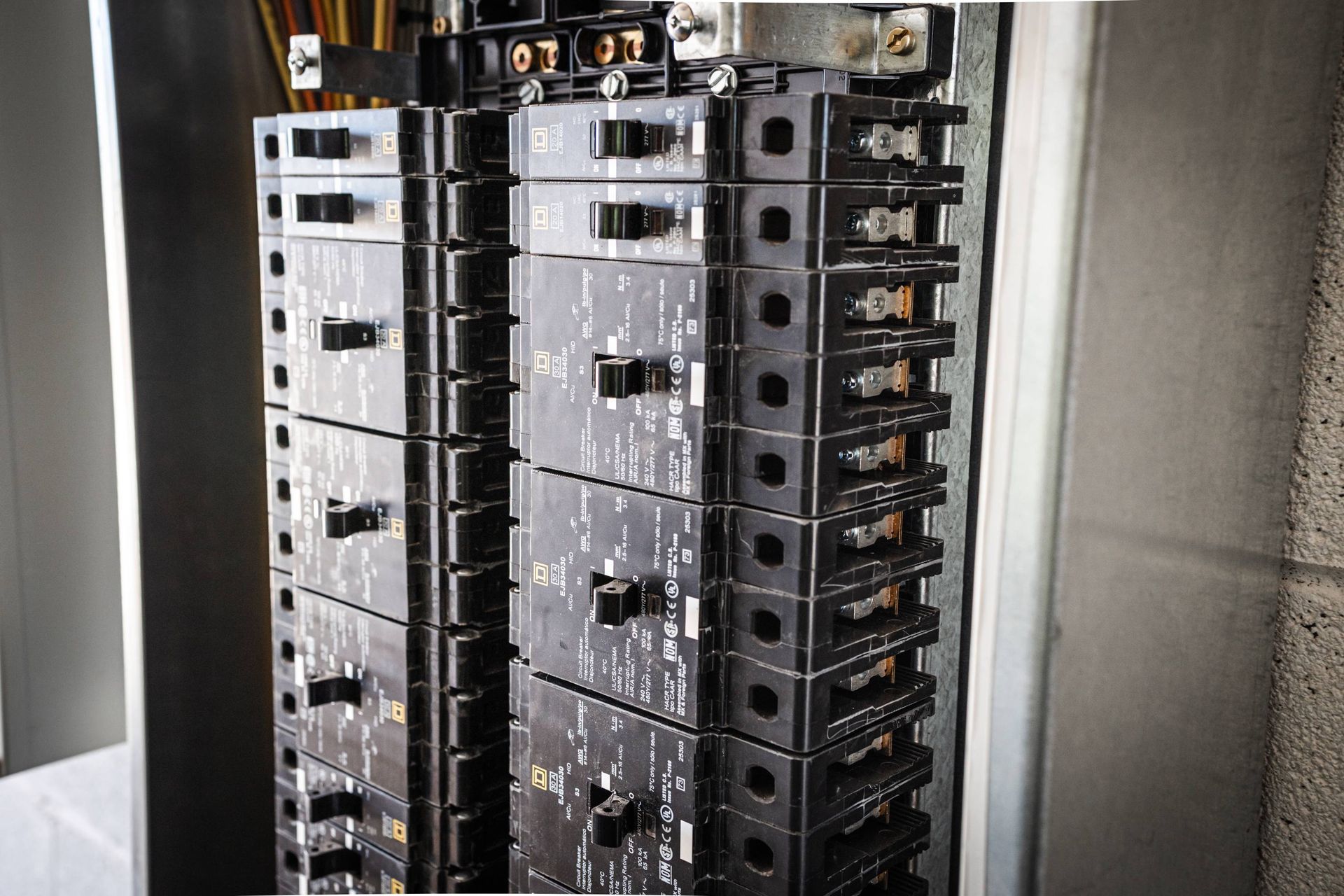 Electrical circuit breakers inside a metal panel. Black breakers in rows.
