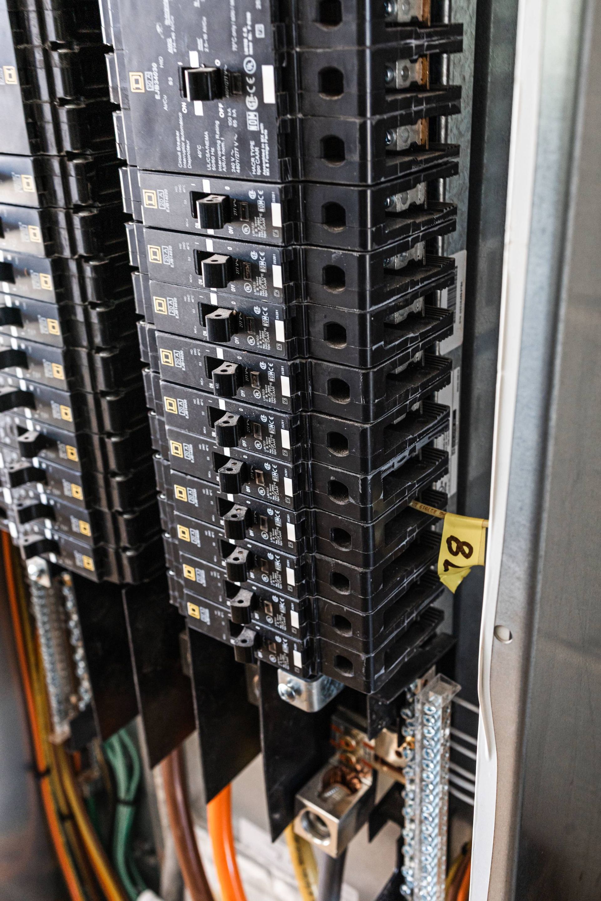 Electrical circuit breaker panel with black switches and labeled sections.