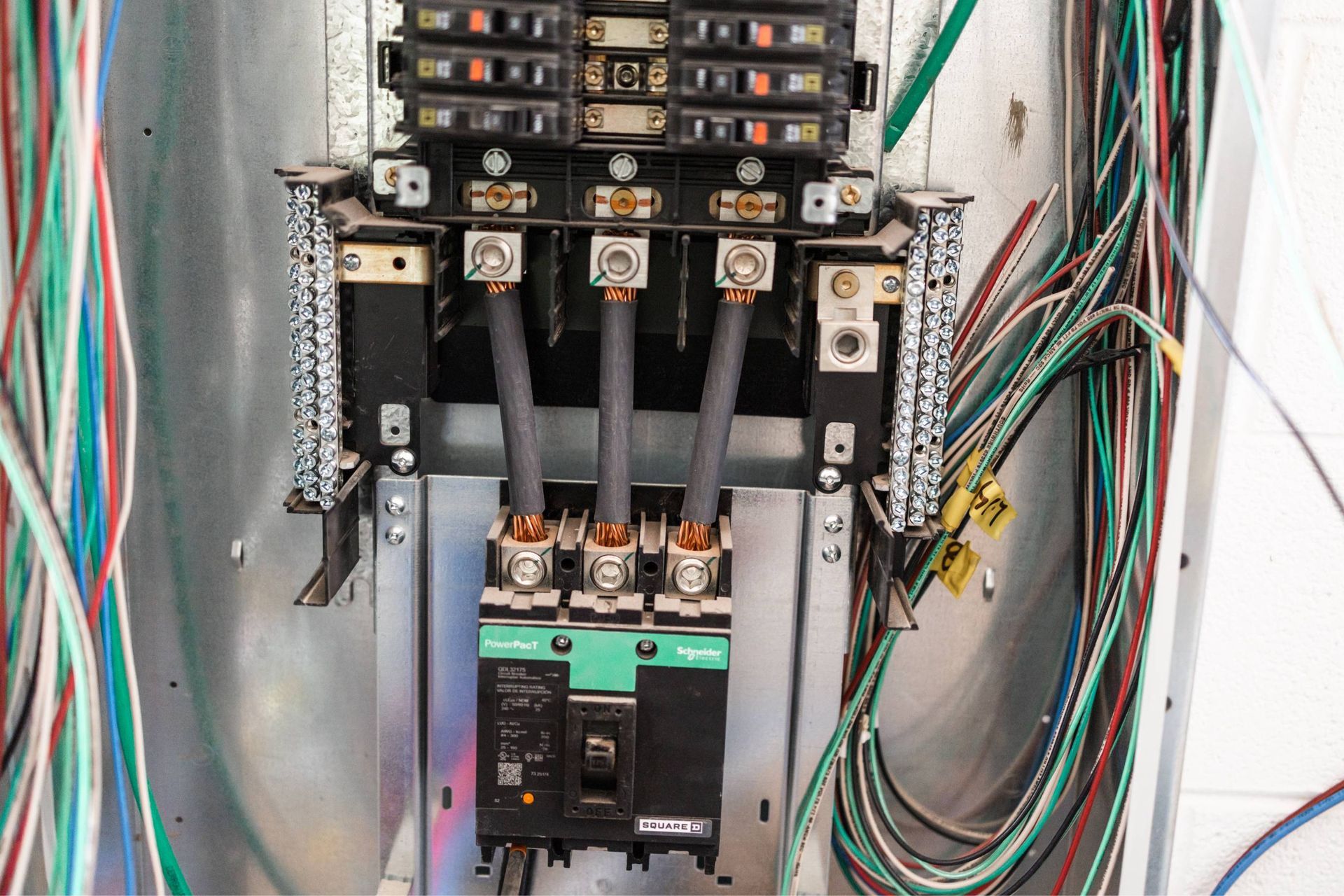 Electrical panel with black circuit breakers and multiple colored wires.